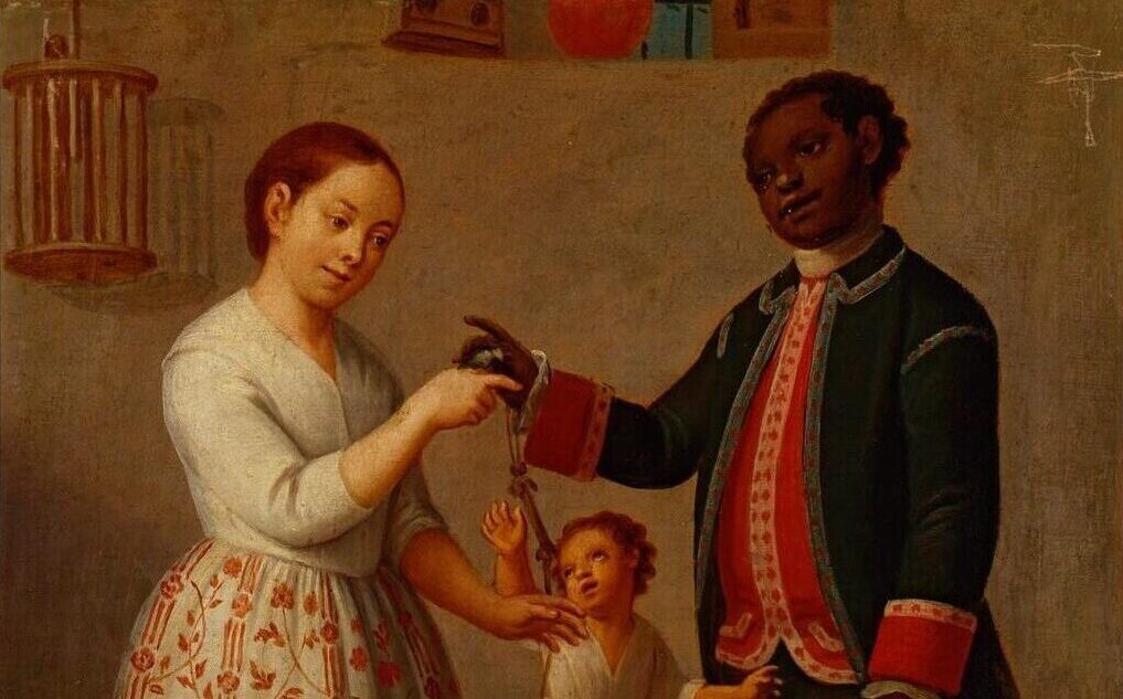 A black man and white woman dangle a string above their child. Click on "Fiote" to navigate to the teaching questions for this word.